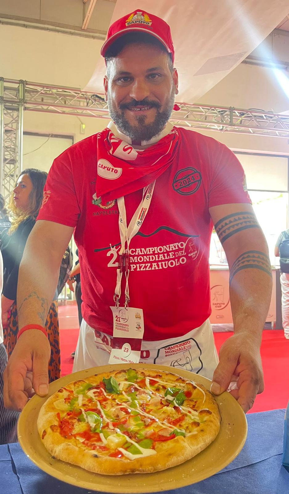 Nuni at the Campionato Mondiale del Pizzaiuolo, holding a freshly baked pizza.