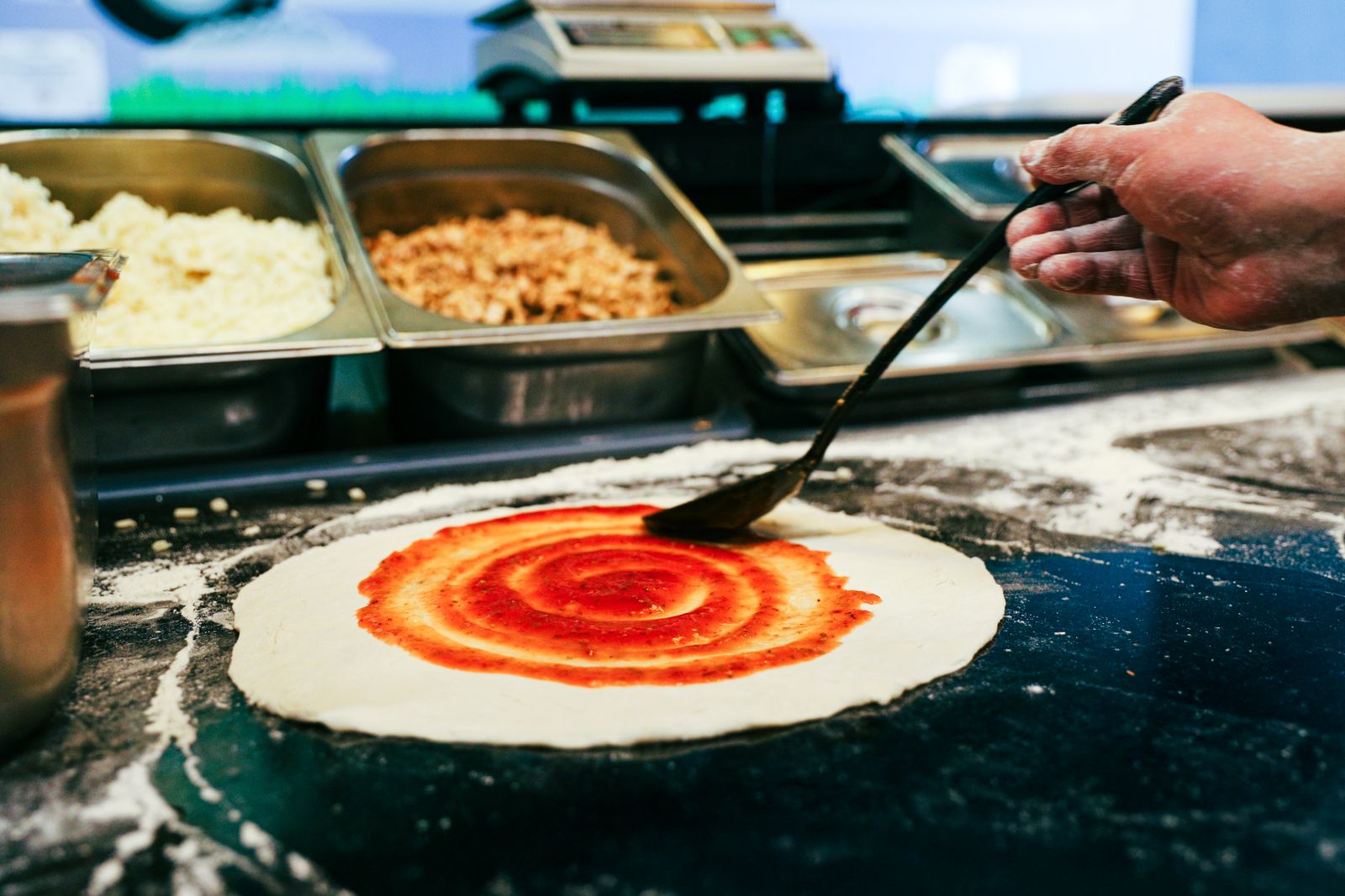 Hand dipping pizza crust into homemade sauce